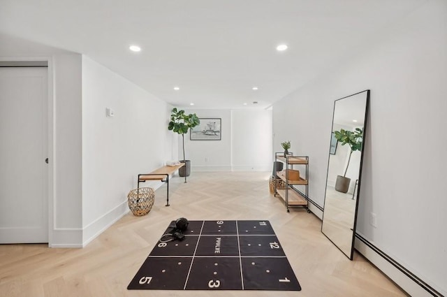 corridor with light parquet floors and a baseboard heating unit