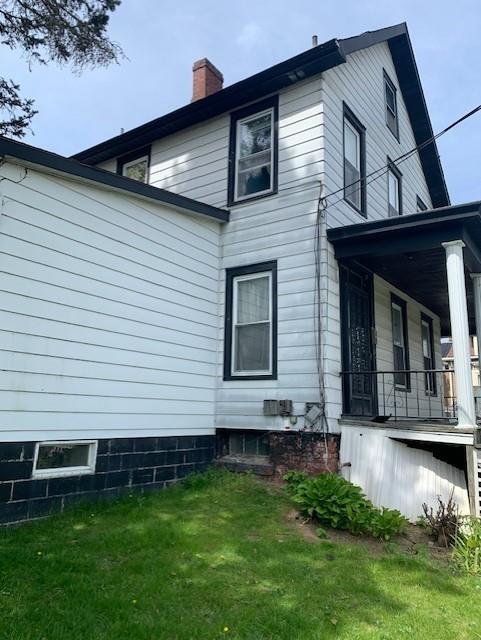 view of side of home with a yard and covered porch