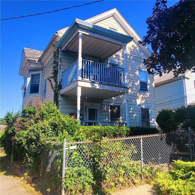 view of front of home with a balcony and a fenced front yard