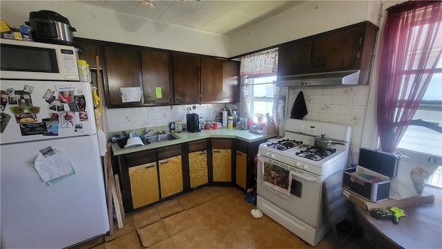 kitchen featuring a sink, backsplash, white appliances, light countertops, and dark brown cabinets