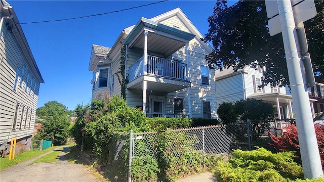 view of side of home with a fenced front yard and a balcony