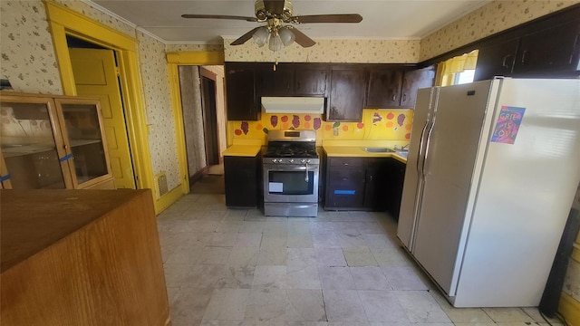 kitchen featuring visible vents, wallpapered walls, range hood, freestanding refrigerator, and stainless steel gas stove