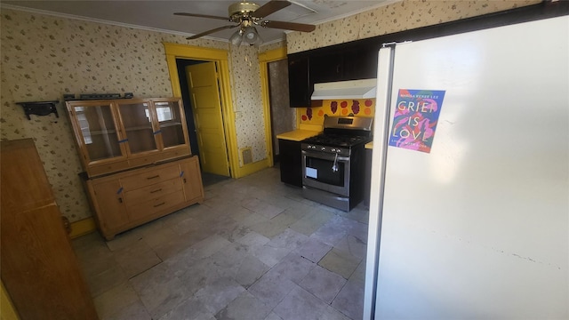 kitchen with under cabinet range hood, gas range, freestanding refrigerator, and wallpapered walls