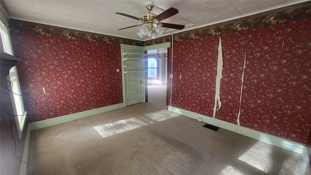 carpeted empty room featuring visible vents, baseboards, a ceiling fan, and wallpapered walls