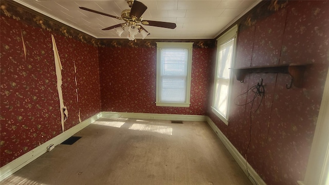 carpeted empty room featuring visible vents, baseboards, a ceiling fan, and wallpapered walls