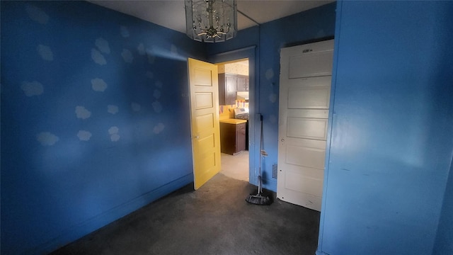 carpeted empty room featuring baseboards and a notable chandelier