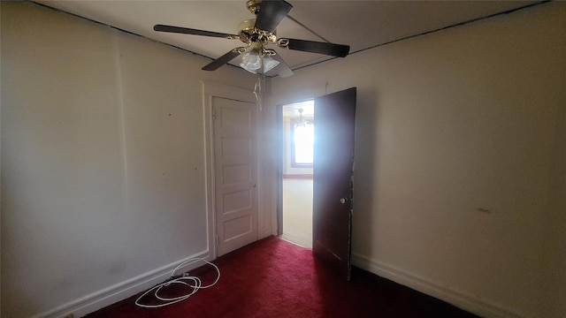 spare room with a ceiling fan, baseboards, and dark carpet