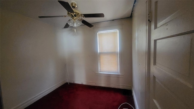 unfurnished room featuring baseboards, dark colored carpet, and ceiling fan