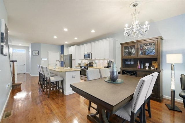 dining room with a chandelier, sink, and light hardwood / wood-style flooring