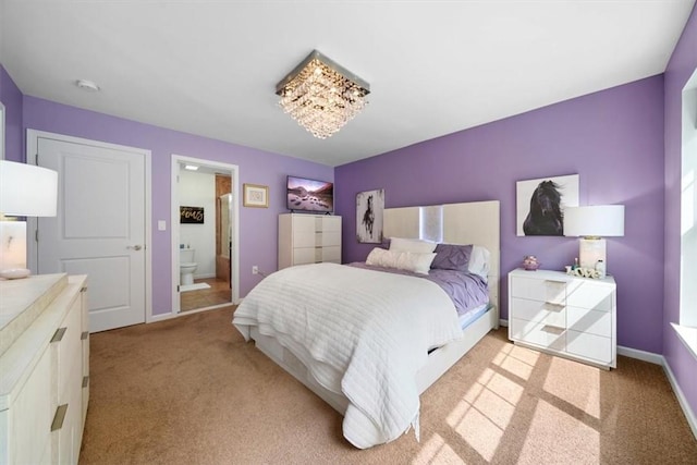 bedroom featuring connected bathroom and light colored carpet