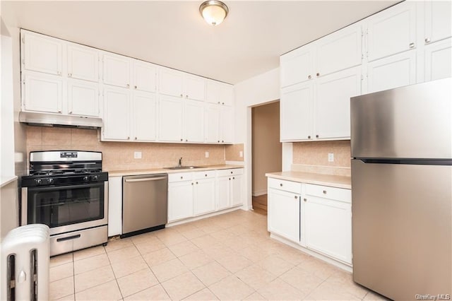 204 W 260th St, Bronx, NY 10471 - kitchen with appliances with stainless steel finishes, under cabinet range hood, light countertops, backsplash, and white cabinets