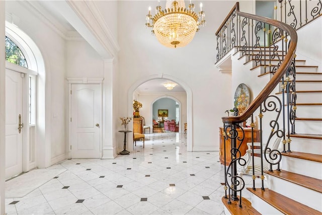 foyer entrance featuring crown molding, a high ceiling, and a chandelier