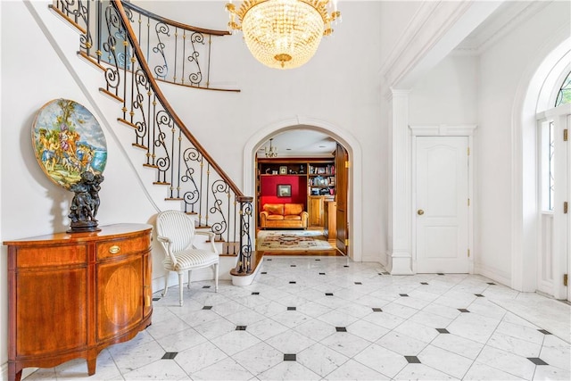 foyer entrance with a towering ceiling, ornamental molding, and a notable chandelier