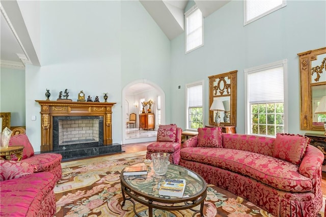 living room with a high end fireplace, a towering ceiling, and a wealth of natural light