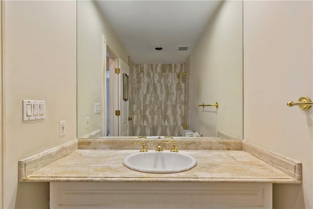 bathroom with a tile shower, vanity, and toilet