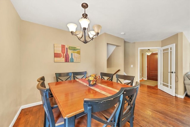 dining space featuring wood-type flooring, french doors, and a chandelier