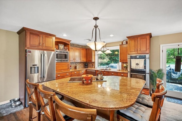 kitchen featuring hanging light fixtures, dark hardwood / wood-style floors, stainless steel appliances, and a wealth of natural light