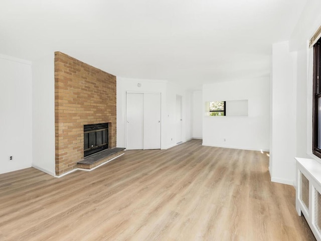 unfurnished living room with a fireplace, light hardwood / wood-style flooring, and radiator heating unit