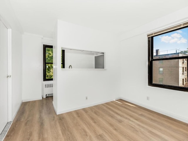 unfurnished room with radiator heating unit, ornamental molding, and light hardwood / wood-style flooring