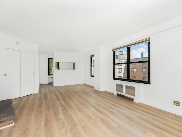 unfurnished living room with radiator and light wood-type flooring