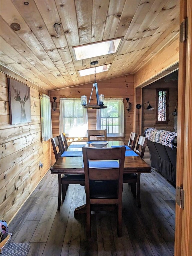 dining room featuring vaulted ceiling with skylight, dark hardwood / wood-style flooring, wood ceiling, and wooden walls