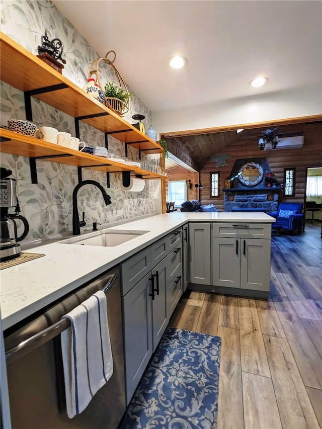 kitchen with wood-type flooring, sink, stainless steel dishwasher, gray cabinets, and kitchen peninsula