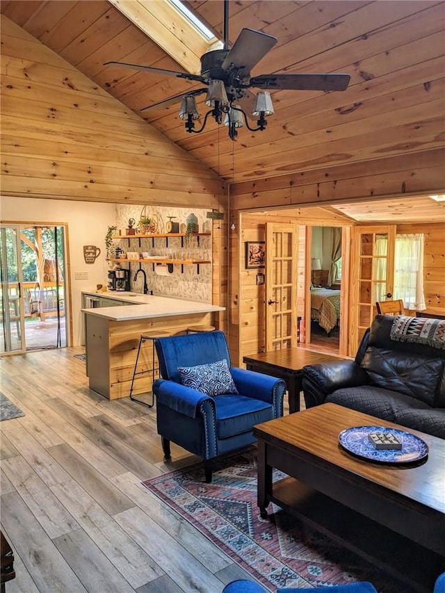 living room featuring wooden ceiling, lofted ceiling with skylight, french doors, ceiling fan, and light wood-type flooring