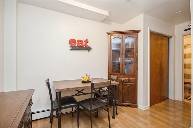 dining space with light hardwood / wood-style flooring and a baseboard heating unit