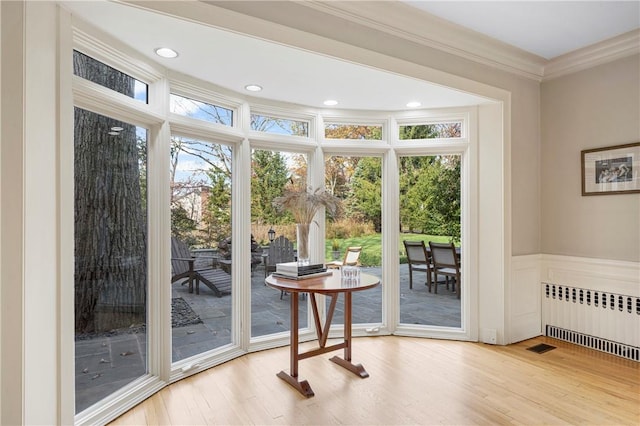 entryway featuring light hardwood / wood-style floors, radiator heating unit, and ornamental molding