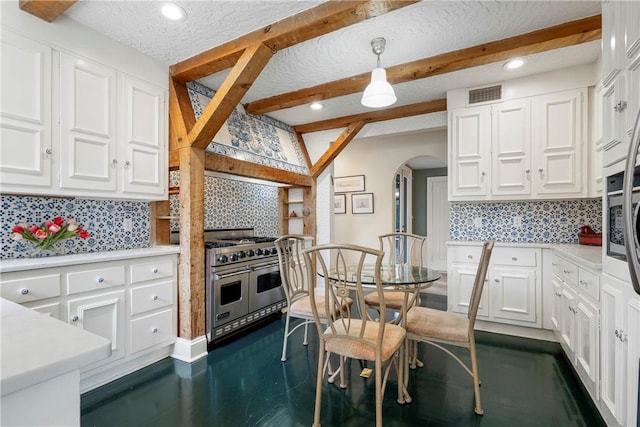 kitchen featuring backsplash, white cabinetry, double oven range, and hanging light fixtures