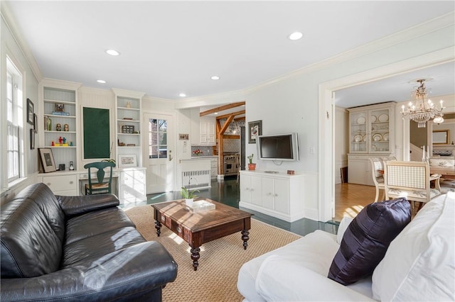 living room featuring radiator heating unit, ornamental molding, light wood-type flooring, and an inviting chandelier