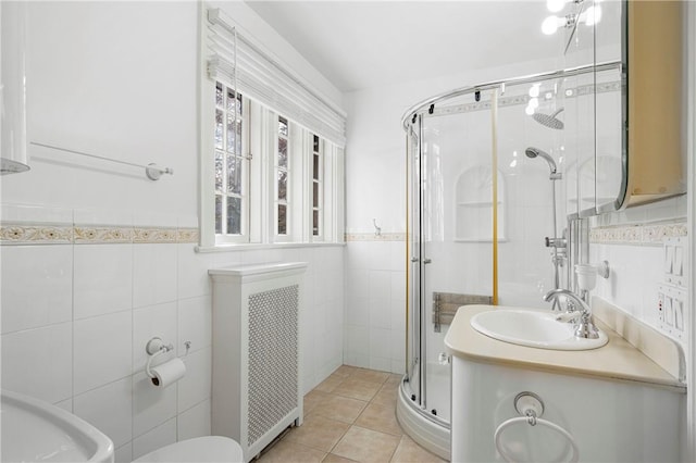 bathroom with vanity, tile patterned flooring, tile walls, an enclosed shower, and radiator heating unit