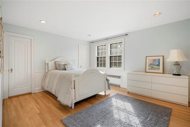 bedroom featuring radiator heating unit and light hardwood / wood-style floors