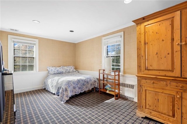 bedroom featuring crown molding, radiator, and multiple windows