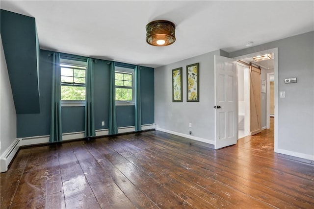 spare room with a barn door and dark hardwood / wood-style flooring