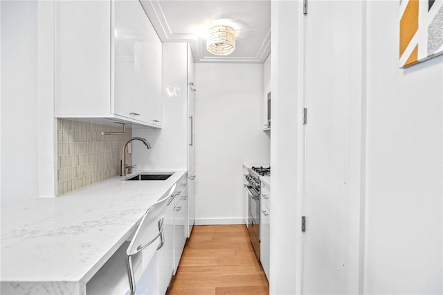 kitchen with white cabinets, sink, light hardwood / wood-style flooring, decorative backsplash, and light stone countertops