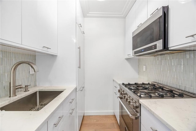 kitchen featuring light stone countertops, tasteful backsplash, stainless steel appliances, sink, and white cabinets