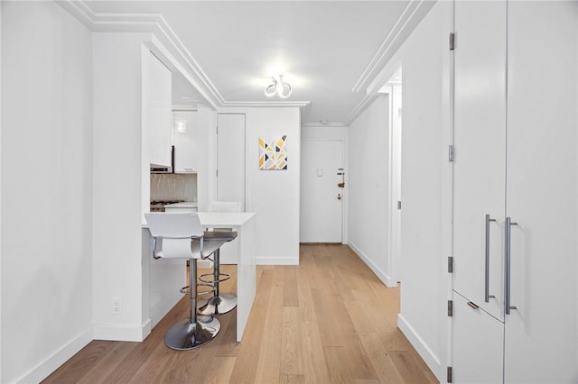 hallway with light hardwood / wood-style floors and crown molding