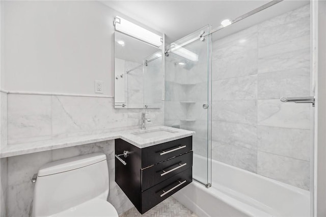 full bathroom with vanity, toilet, bath / shower combo with glass door, and tile walls