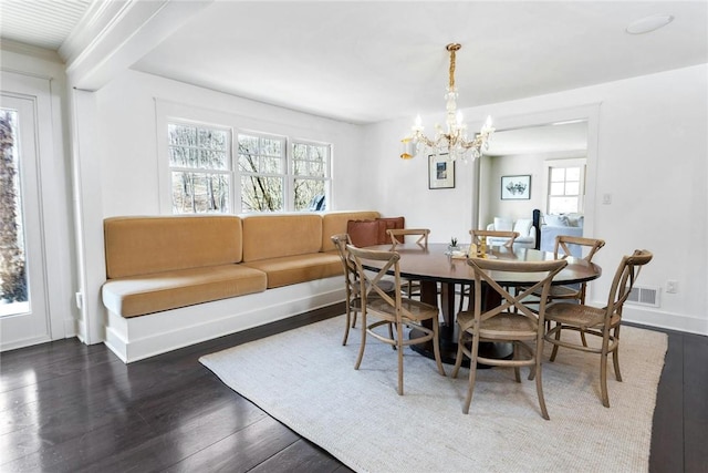 dining space with a chandelier, dark wood-type flooring, and a healthy amount of sunlight