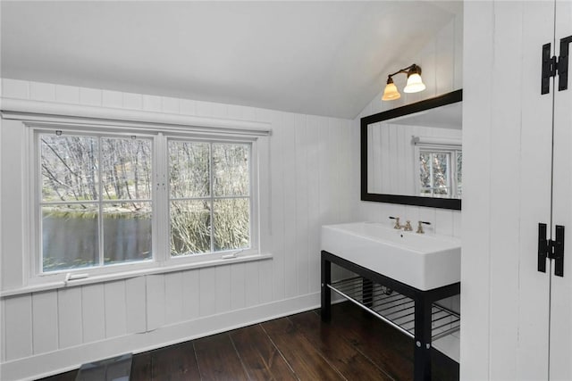 bathroom with hardwood / wood-style floors, vaulted ceiling, a healthy amount of sunlight, and wood walls