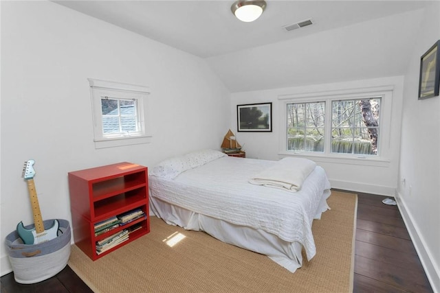 bedroom featuring hardwood / wood-style floors, vaulted ceiling, and multiple windows