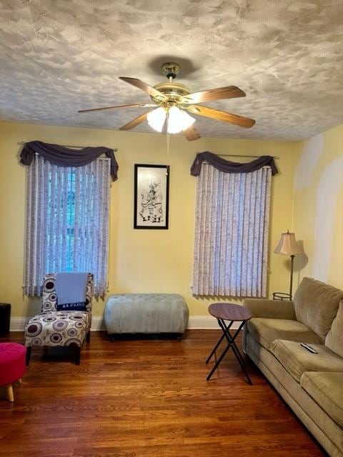 living room featuring ceiling fan, wood-type flooring, and a textured ceiling