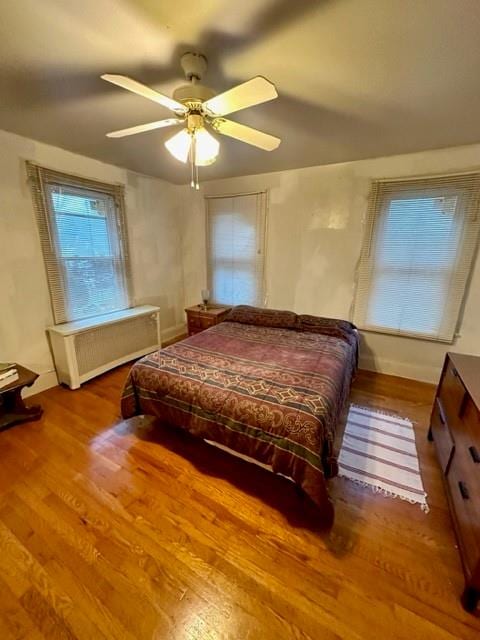 bedroom with hardwood / wood-style floors, ceiling fan, and radiator