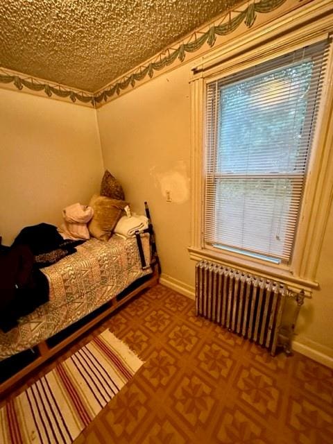 bedroom with radiator heating unit and a textured ceiling