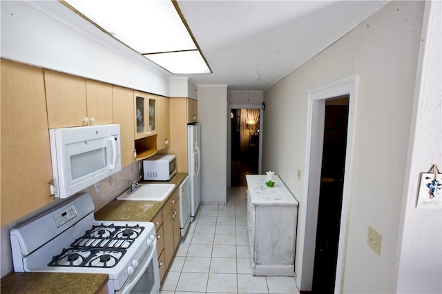 kitchen with light tile patterned floors, white appliances, and sink