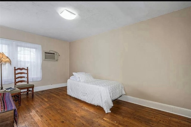 bedroom featuring dark hardwood / wood-style flooring and an AC wall unit