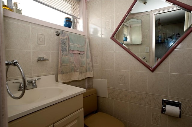 bathroom featuring vanity, tile walls, and toilet