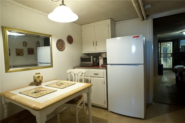 kitchen featuring white refrigerator, white cabinetry, and hanging light fixtures