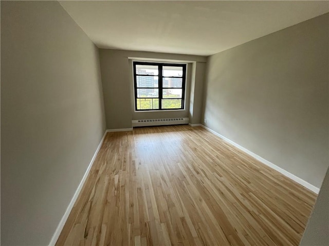 spare room with a baseboard radiator and light wood-type flooring